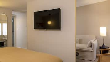 A hotel room with a bed, a television mounted on the wall, a sofa, and a lamp.