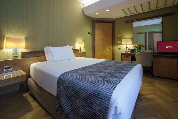 Une chambre d’hôtel avec un grand lit, des lampes de chevet, un bureau avec un ordinateur portable et une télévision.