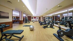 A gym with exercise equipment, wooden floors, and a large mirror. - Exe Majestic (Naples)