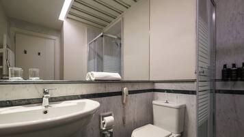 Un baño con lavamanos, inodoro y cabina de ducha de vidrio.