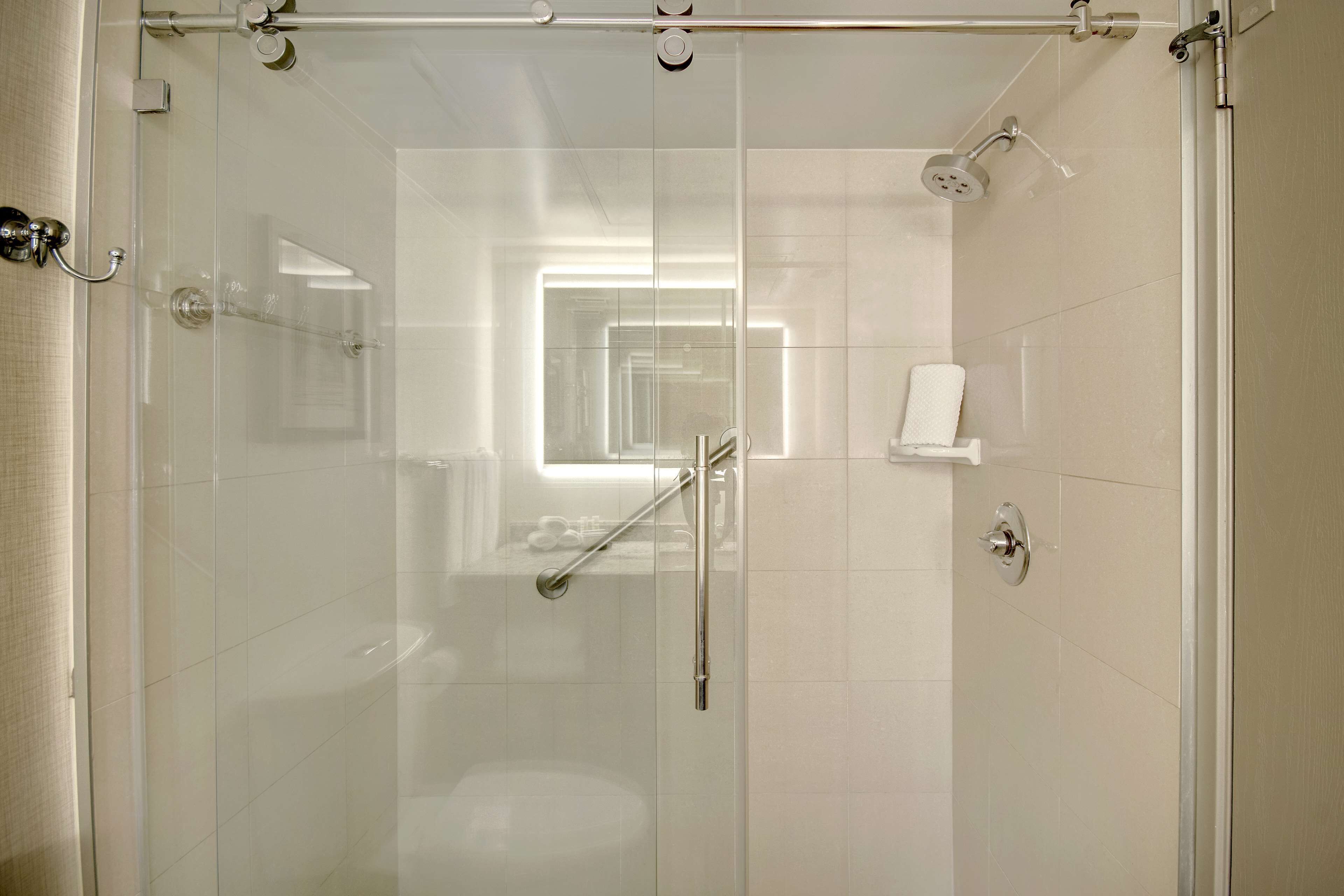 Ein modernes Badezimmer mit Duschkabine aus Glas, sichtbarer Toilette und Handtuchhalter.