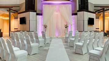 Une cérémonie de mariage avec des chaises blanches et une allée également blanche.