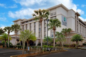 A hotel with a modern facade, palm trees, and a clear sky. - Embassy Suites by Hilton Jacksonville Baymeadows (Jacksonville)