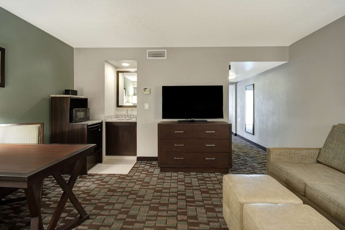 Habitación de hotel con comedor, kitchenette, televisión de pantalla plana y sofá.