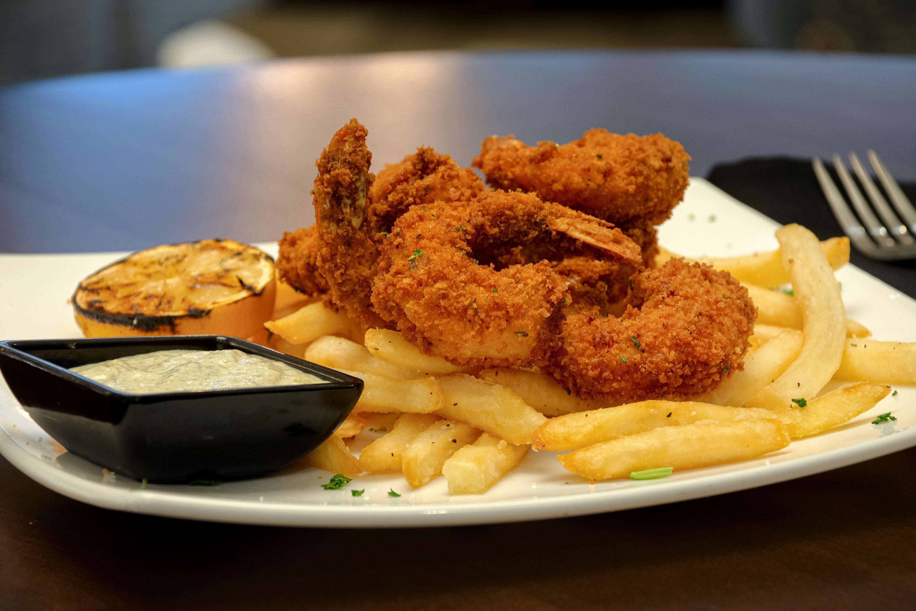 A plate of fried chicken, French fries, and a small bowl of dipping sauce.