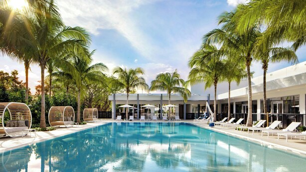 Una piscina con sillas de descanso y palmeras.