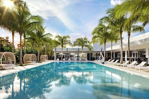 A swimming pool with lounge chairs and palm trees.