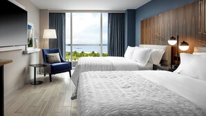 Habitación de hotel con dos camas, un televisor, una silla, una lámpara y vistas al cielo.