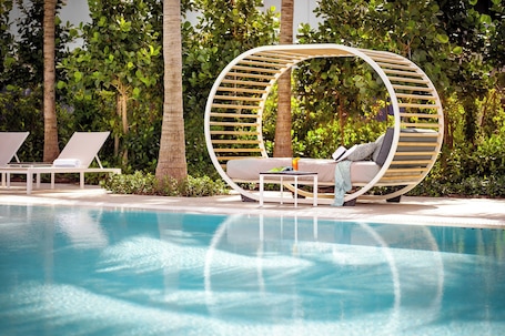 Una piscina al aire libre, sombrillas, sillones reclinables de piscina