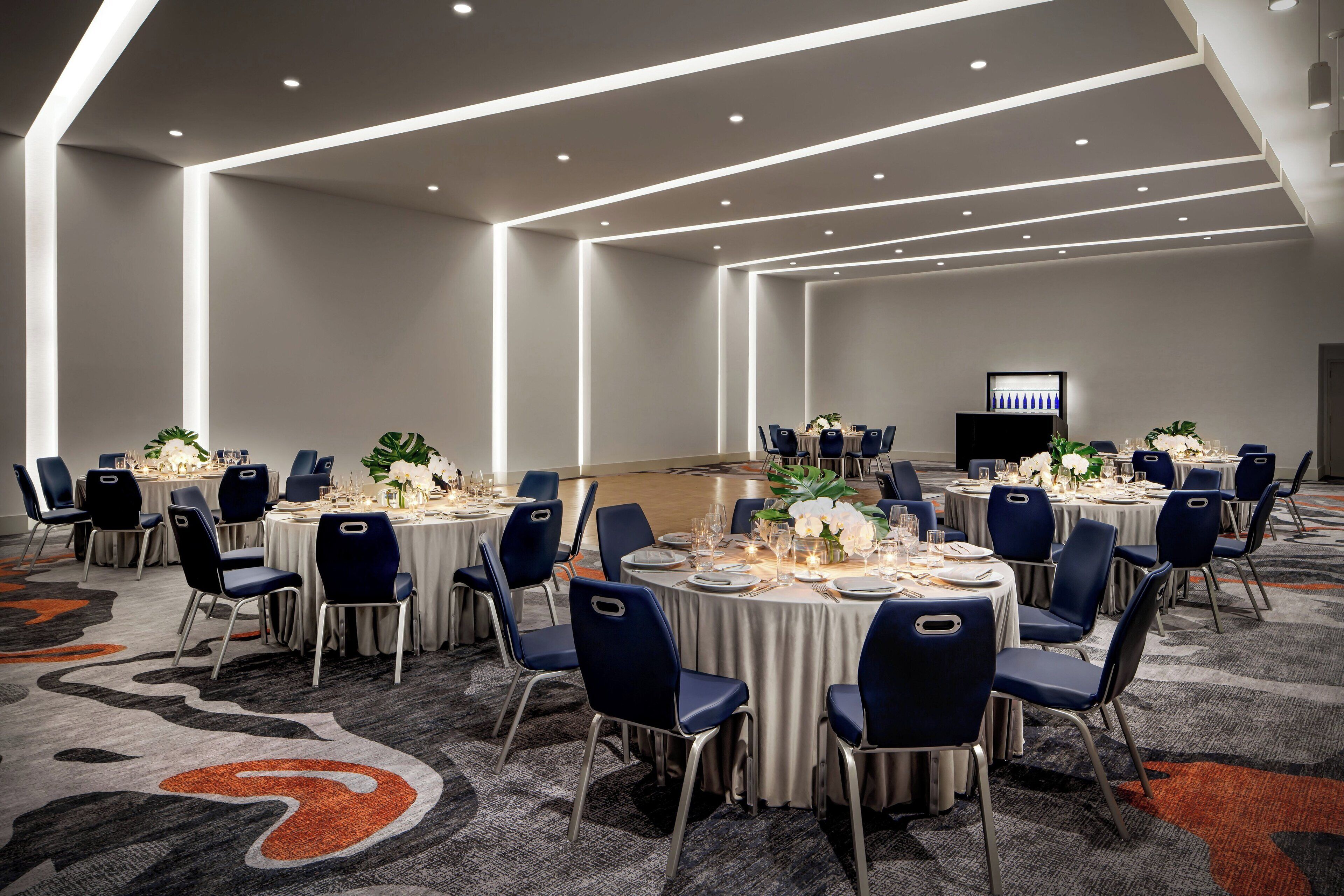 A conference room with round tables, blue chairs, and a carpeted floor.