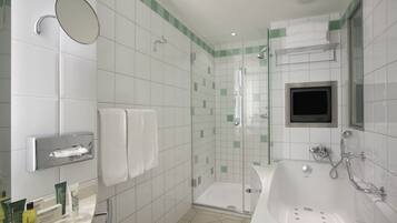 A modern bathroom with a glass-enclosed shower, a large bathtub, and a vanity with a mirror and towel rack.