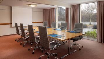 A conference room with a long table, six chairs, and a projector screen.