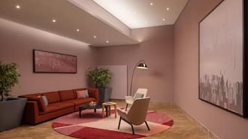 Una sala moderna con un sofá rojo, un sillón color beige, una mesita de centro y una lámpara de pie. Hay dos plantas en macetas y un cuadro abstracto grande en la pared.