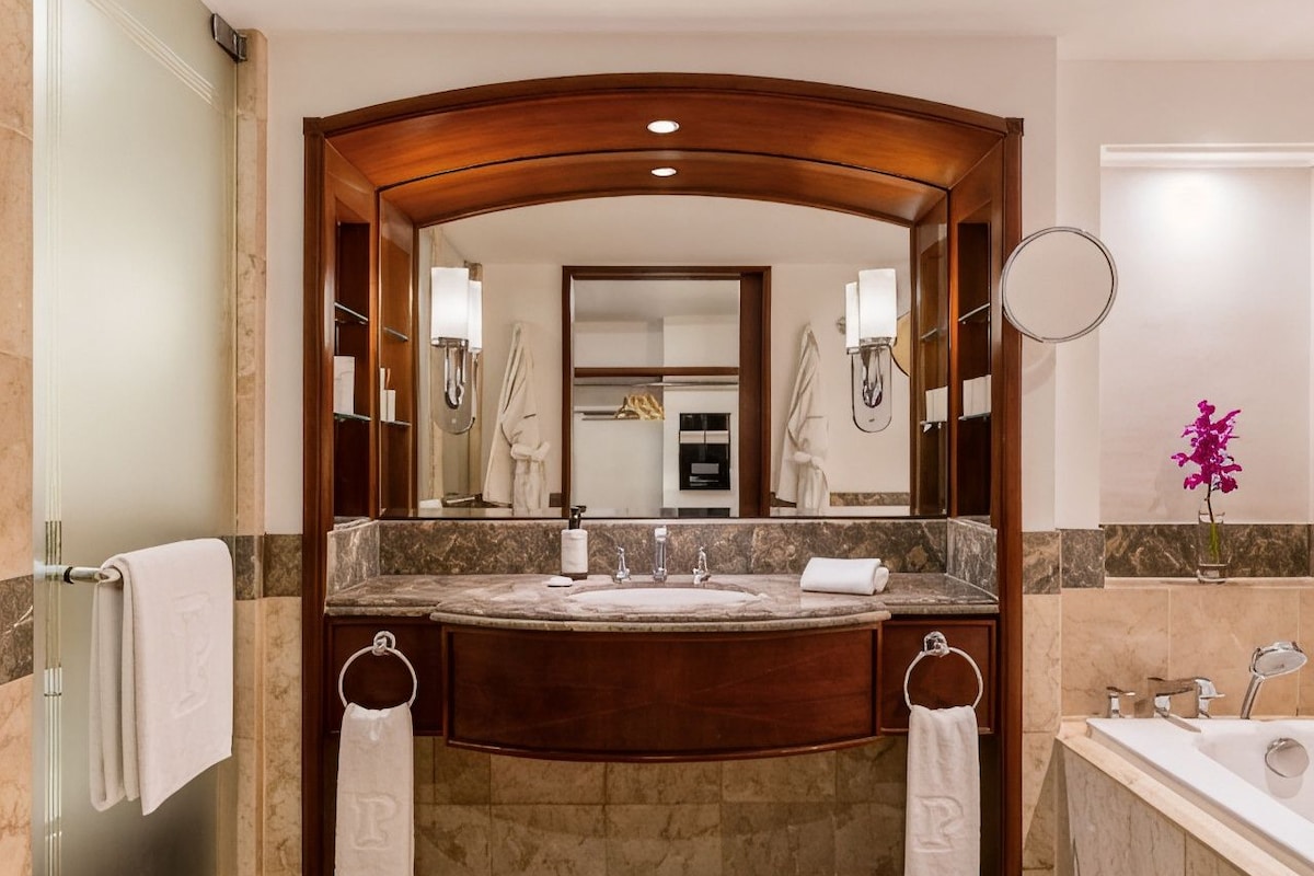 Un baño con lavamanos doble, un espejo grande y una bañera.