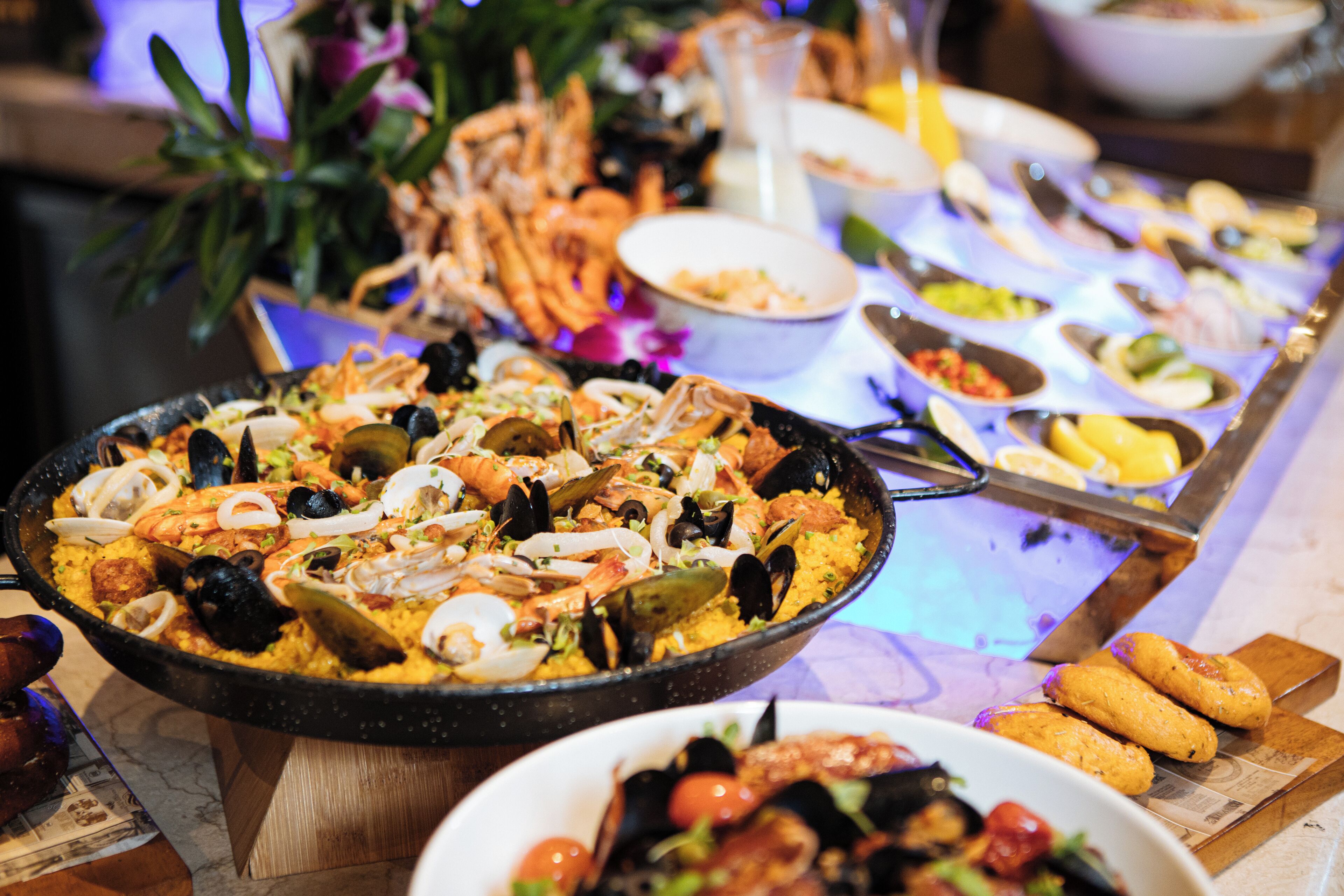 A seafood buffet with a variety of dishes including shrimp, mussels, and a large paella.
