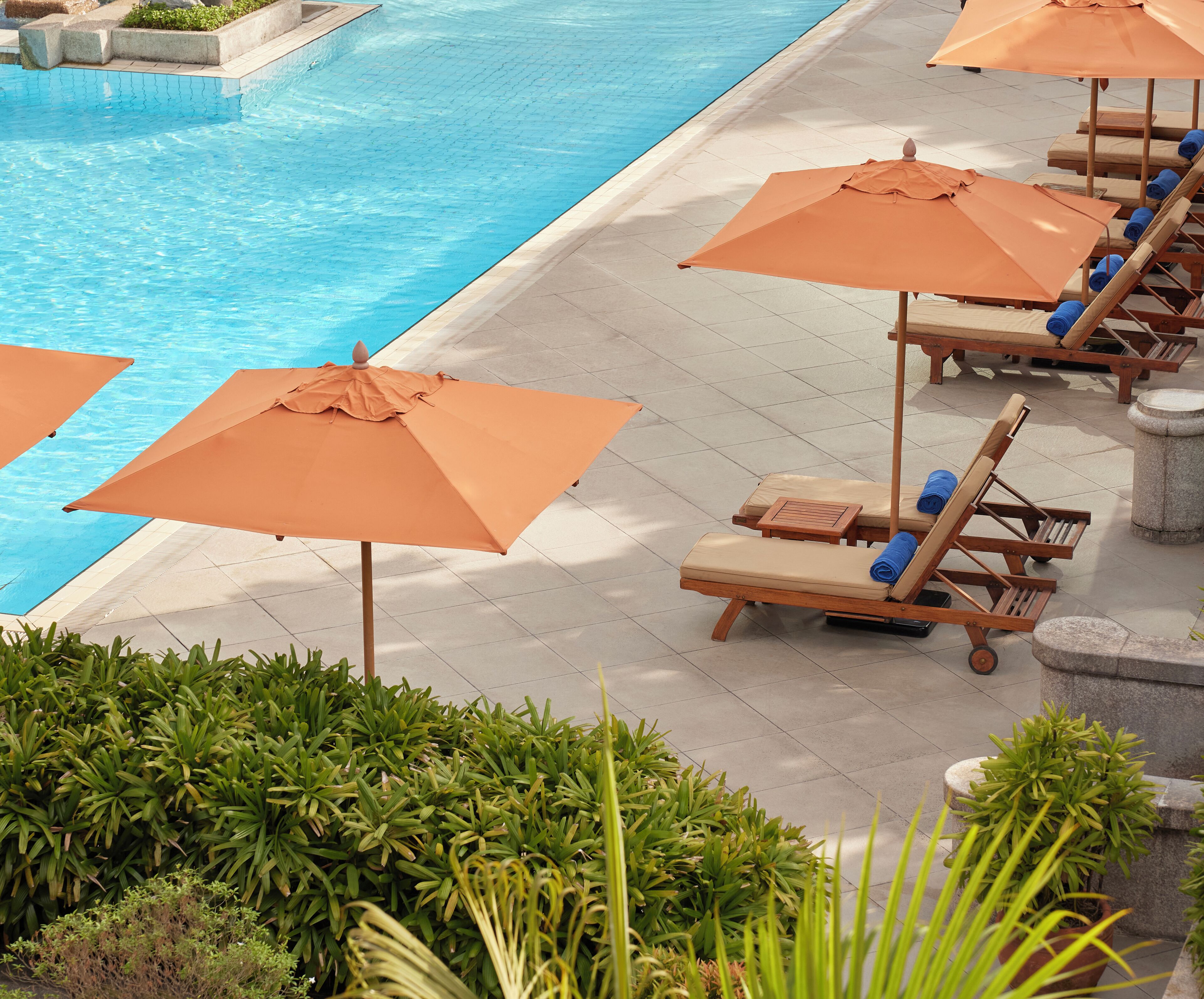 A poolside area with lounge chairs and orange umbrellas.