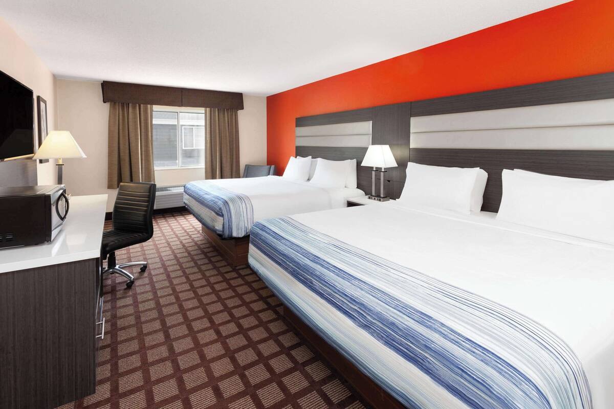 Ett hotellrum med två sängar, ett skrivbord med en dator och en tv.