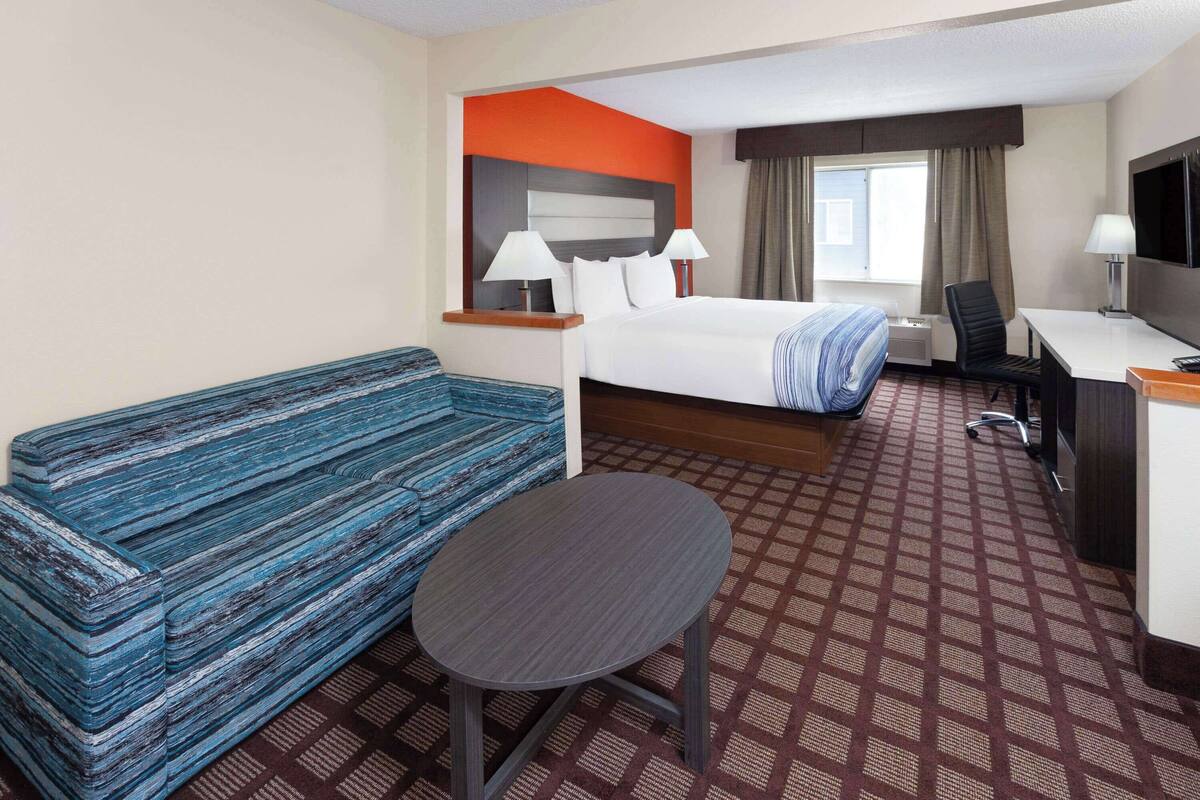 Ett hotellrum med en säng, ett skrivbord, en stol, ett litet bord och en soffa.