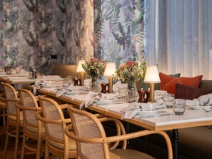 Un restaurante con mesas de madera, sillas de mimbre y centros de mesa florales.