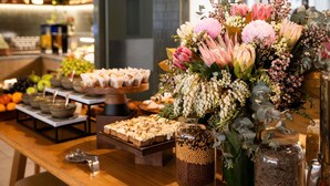 A buffet table with various food items and a floral centerpiece. - Novotel Sydney City Centre (Sydney)