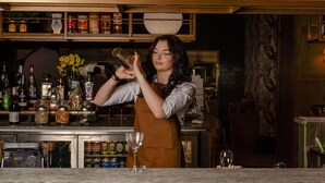 A bartender preparing a drink behind a bar with various bottles and glasses. - Novotel Sydney City Centre (Sydney)