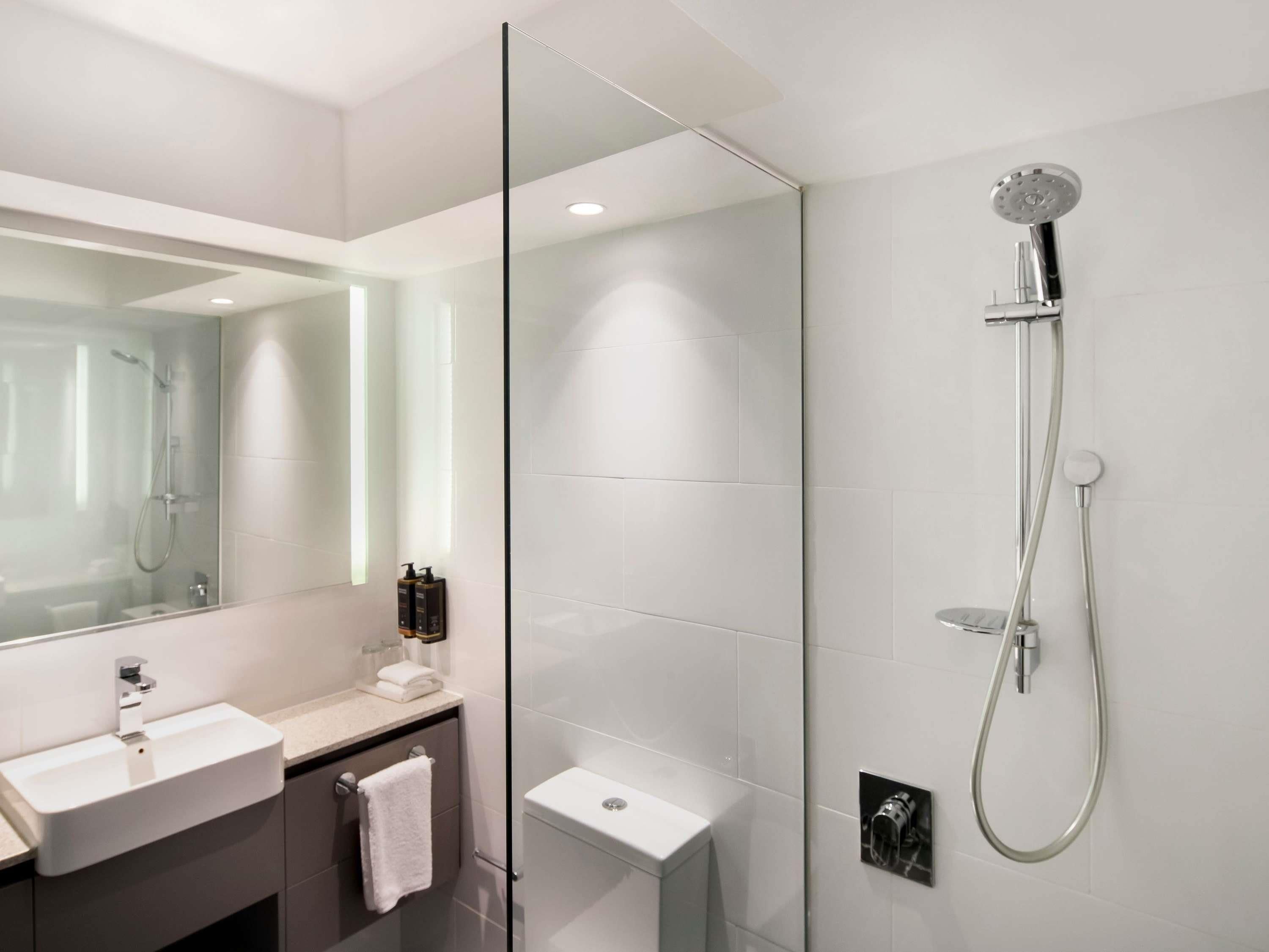 A modern bathroom with a glass-enclosed shower, a white sink, and a large mirror.