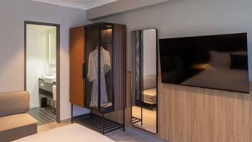 Una habitación de hotel moderna con una cama, una zona de estar, un armario y un espejo grande.
