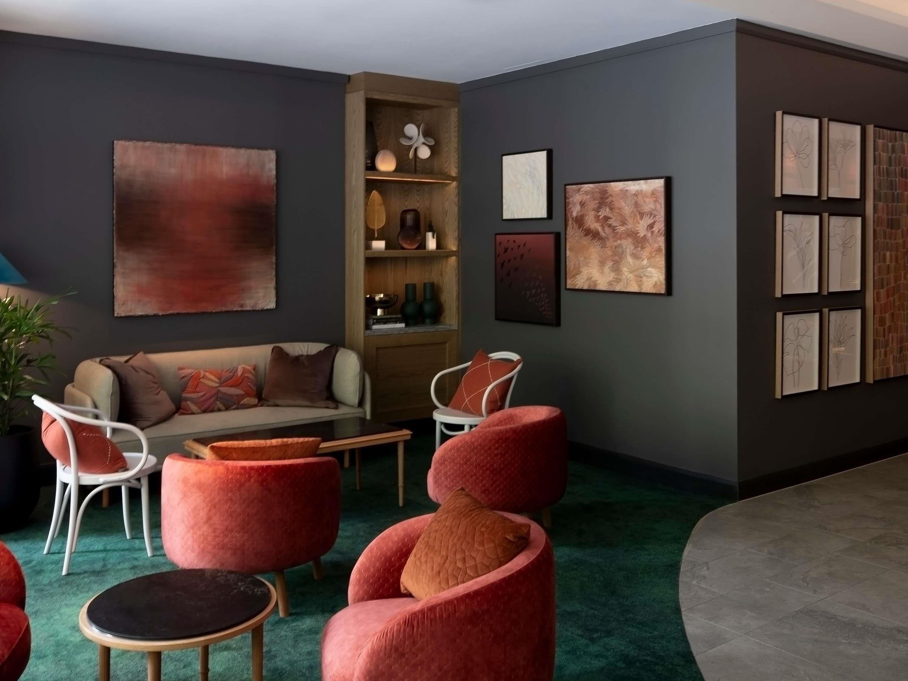 A modern living room with a sofa, red chairs, a coffee table, and artwork on the walls.