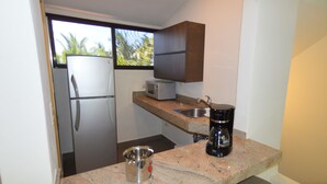 A compact kitchen with a refrigerator, microwave, coffee maker, and a small sink. There are two stools at the counter. - Sina Suites Cancún - Adults Only (Cancun)