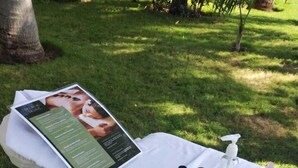 A white towel laid out on grass with a brochure, a bottle of hand sanitizer, and a small bottle of essential oils. - Sina Suites Cancún - Adults Only (Cancun)