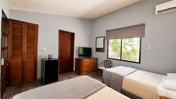Quarto com duas camas, televisão, penteadeira e guarda-roupa.