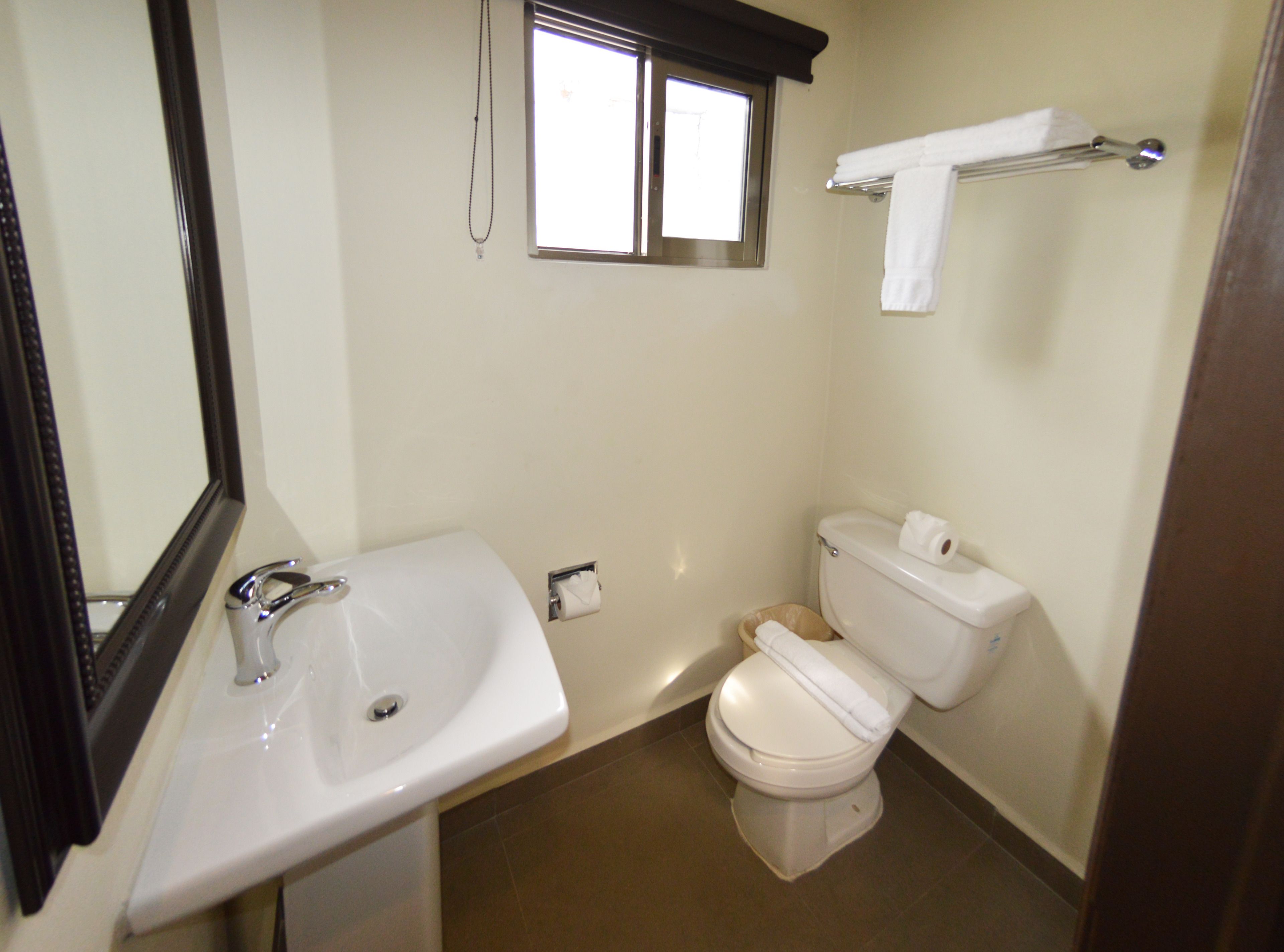 A bathroom with a sink, toilet, and a window.
