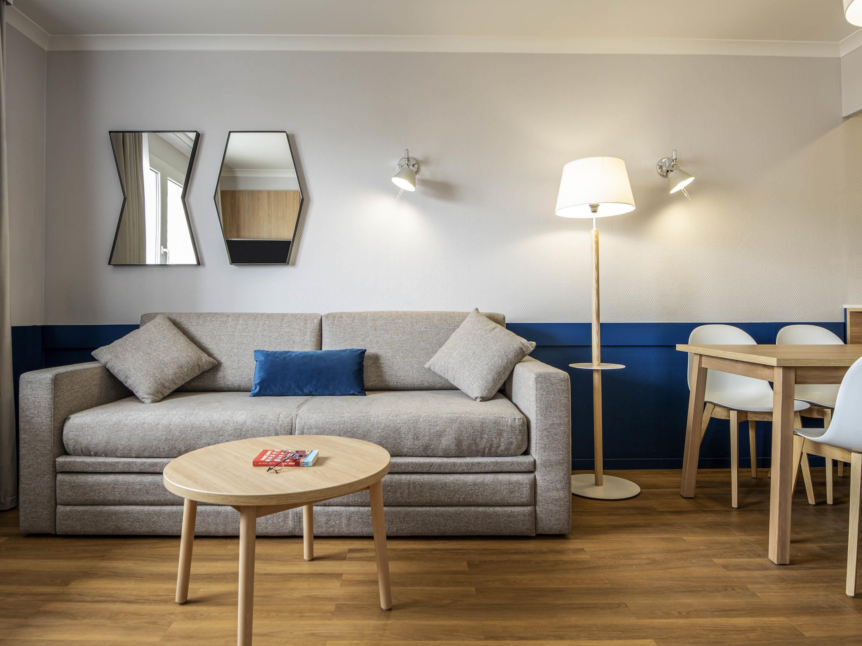 A modern living room with a sofa, a round table, and a floor lamp.