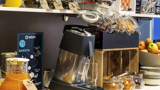 A coffee station with a coffee machine, jars of coffee, and a sign for 'Oadagio Barista'. - Aparthotel Adagio La Defense Kleber (Courbevoie)