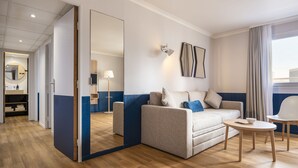 A modern hotel room with a sofa, a small round table, and a mirror. - Aparthotel Adagio La Defense Kleber (Courbevoie)
