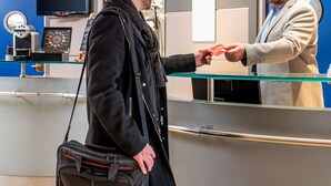 A man in a black coat handing a red card to another man in a grey suit. - Aparthotel Adagio La Defense Kleber (Courbevoie)