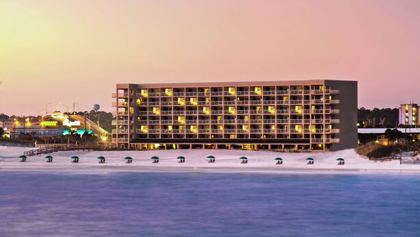 Ein mehrstöckiges Hotel mit modernem architektonischen Design, mit Balkonen und Blick auf das Wasser.