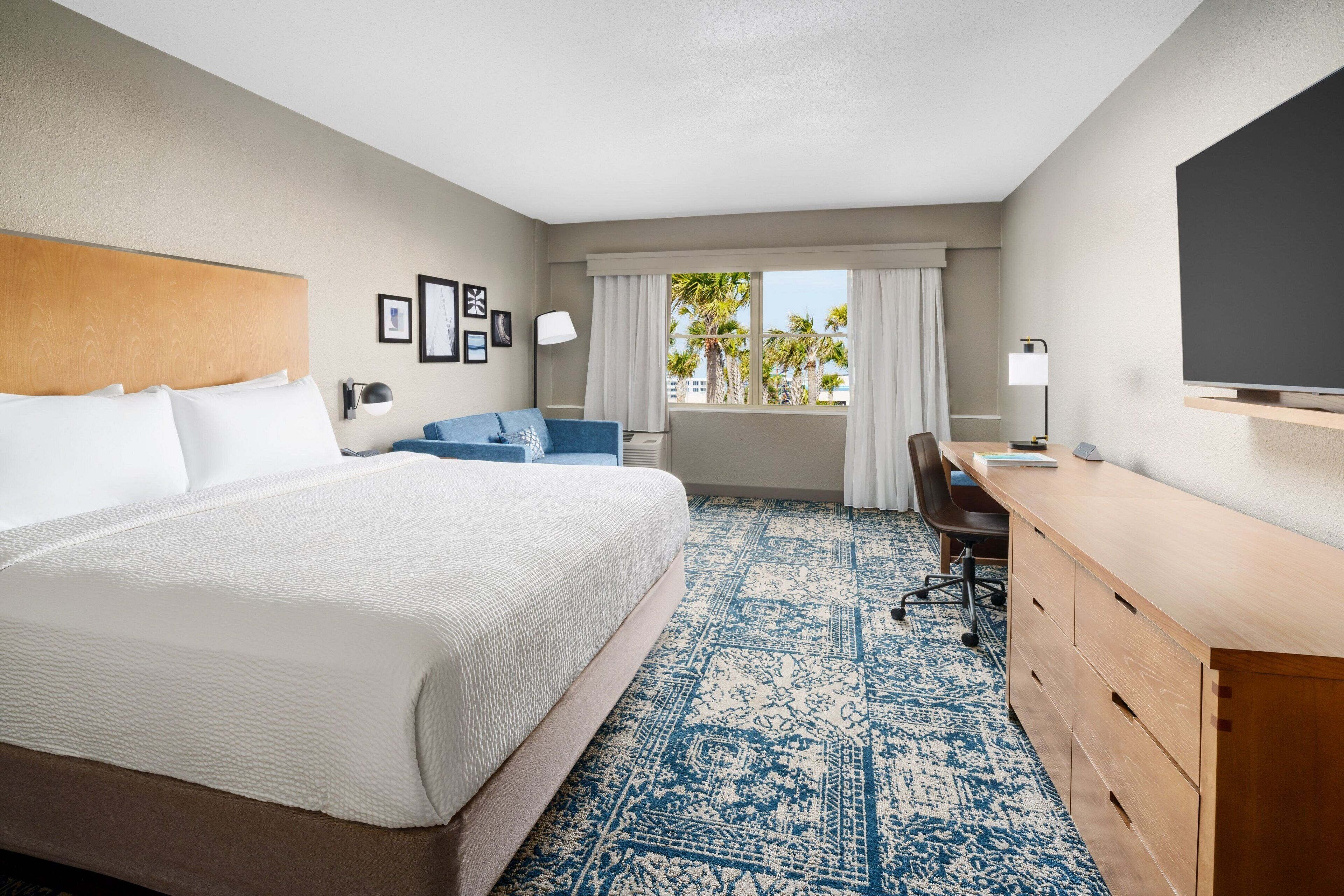 Une chambre d’hôtel avec un grand lit, un bureau, une chaise et un téléviseur.