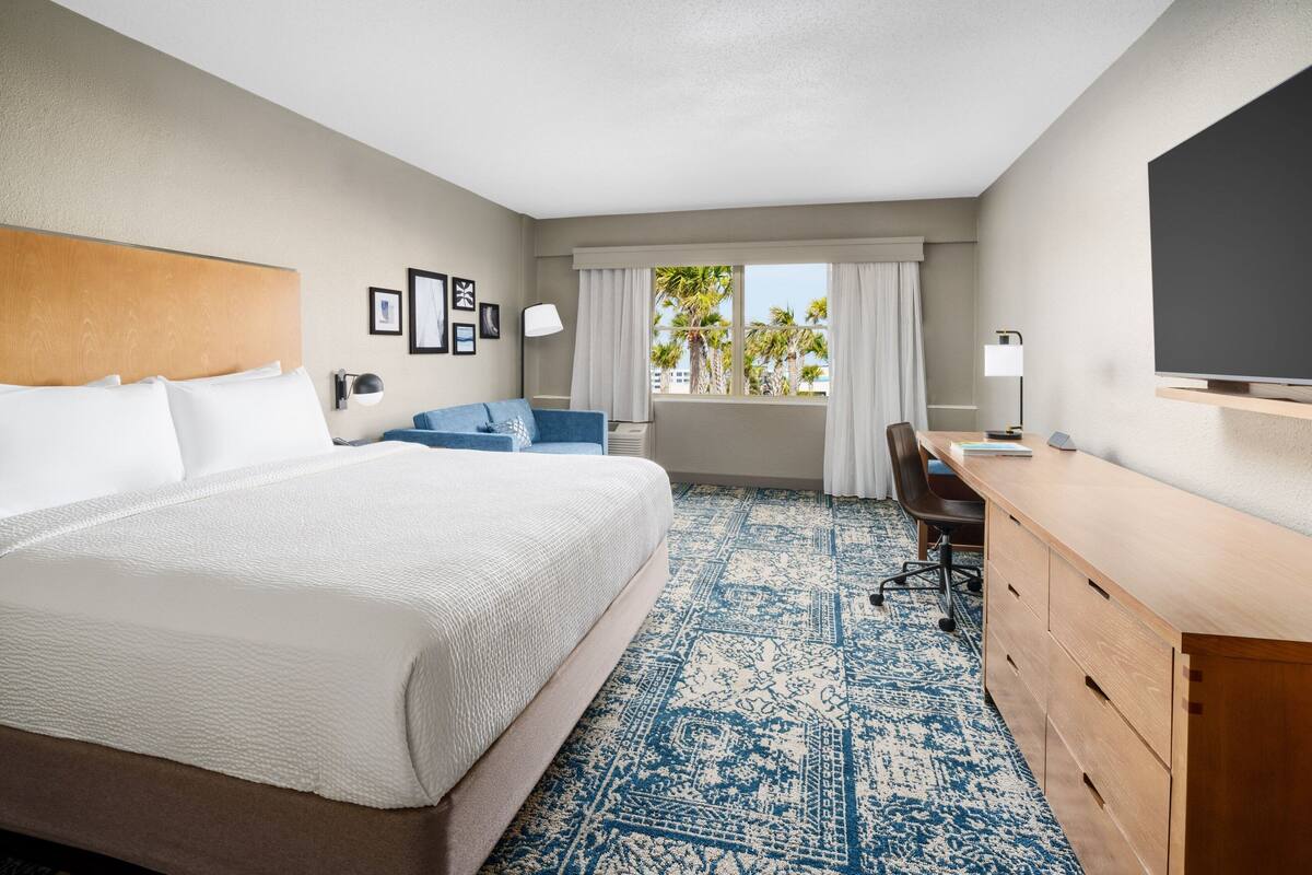 Een hotelkamer met een groot bed, een bureau, een stoel en een televisie.