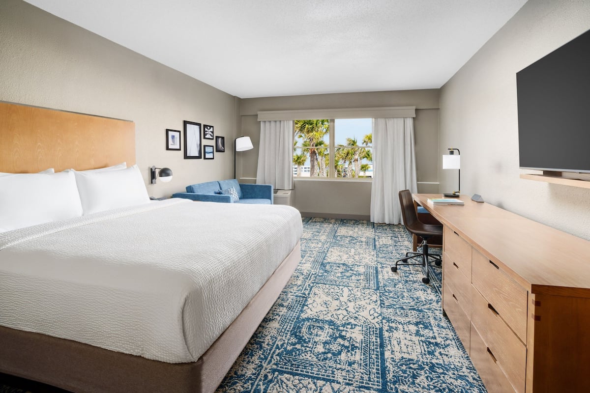 Une chambre d’hôtel avec un grand lit, un bureau, une chaise et un téléviseur.