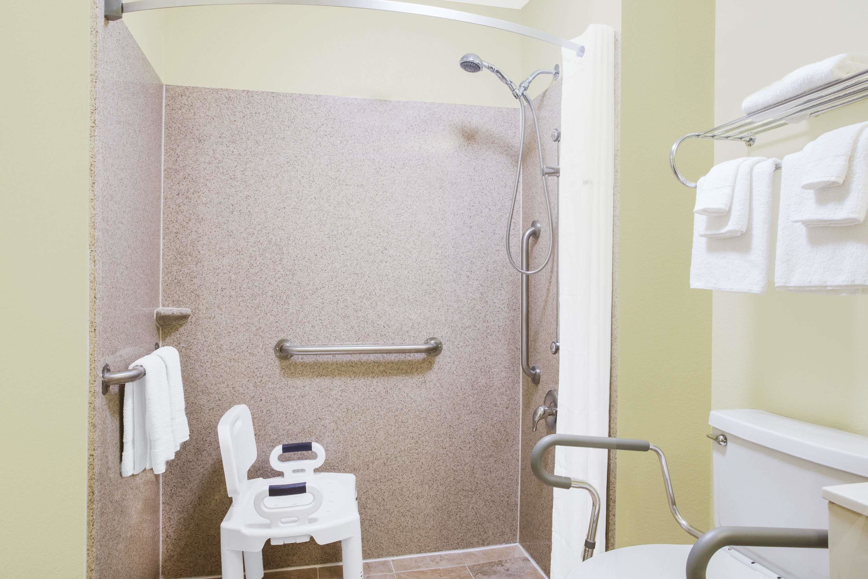 Un baño con ducha, inodoro y una silla.