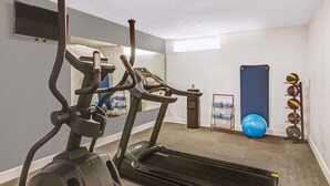 Un gimnasio en casa con cintas de correr, un saco de boxeo y una estantería con pelotas de ejercicio.