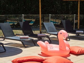 Outdoor lounge chairs and an inflatable flamingo decoration on a tiled patio.