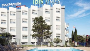 A hotel with a swimming pool, lounge chairs, and a sign reading 'Courtepaille Combi Air.' - ibis Toulon La Seyne Sur Mer (La Seyne-sur-Mer)