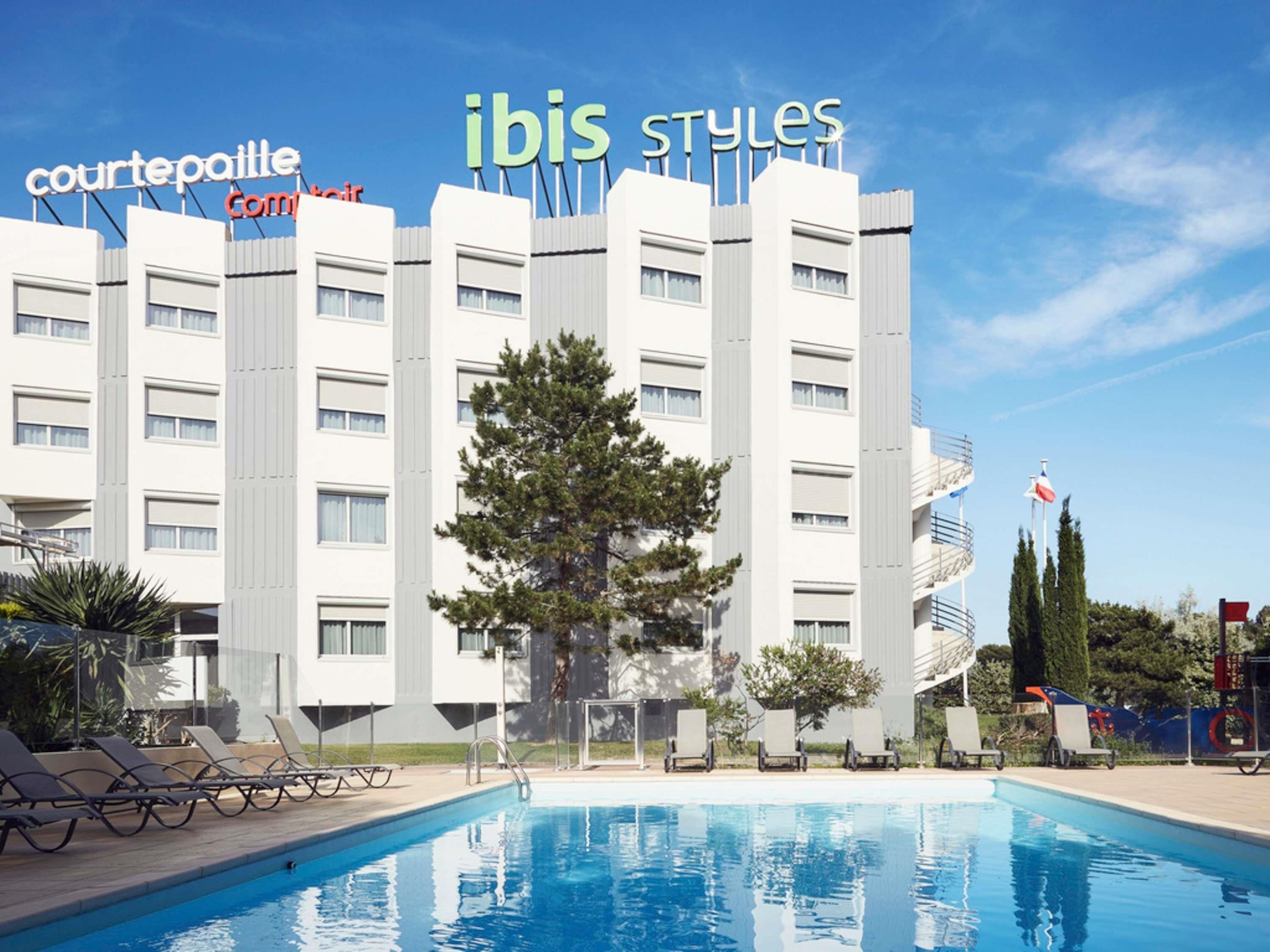Ein Hotel mit Schwimmbad, Liegestühlen und einem Schild mit der Aufschrift 'Courtepaille Combi Air'.