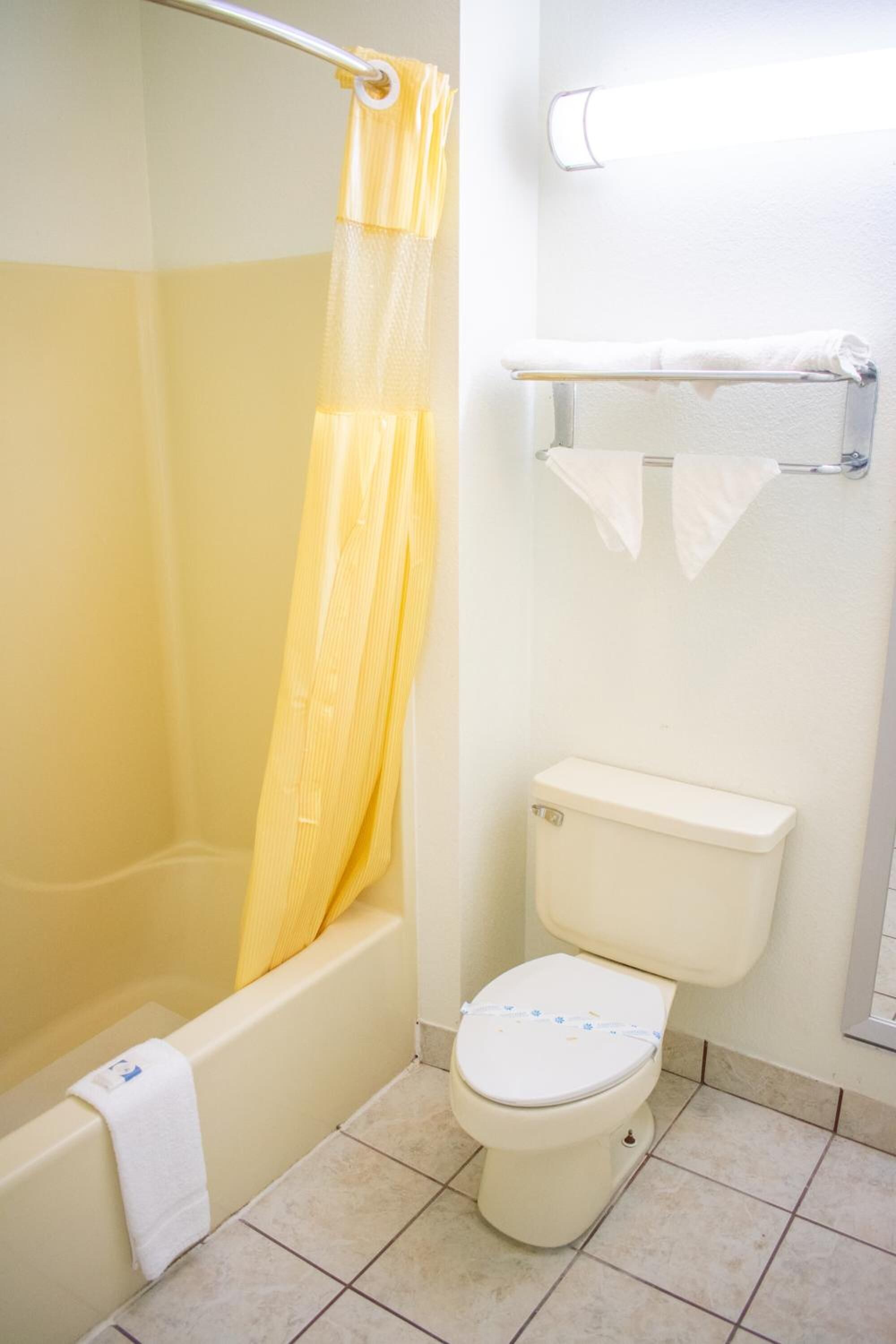 Un baño con bañera, inodoro y cortina de ducha.