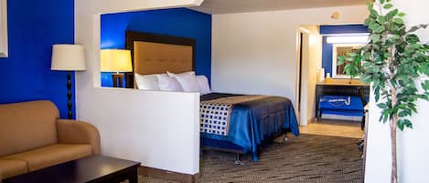 Ein Hotelzimmer mit Bett, Sofa, Schreibtisch und einer Zimmerpflanze.