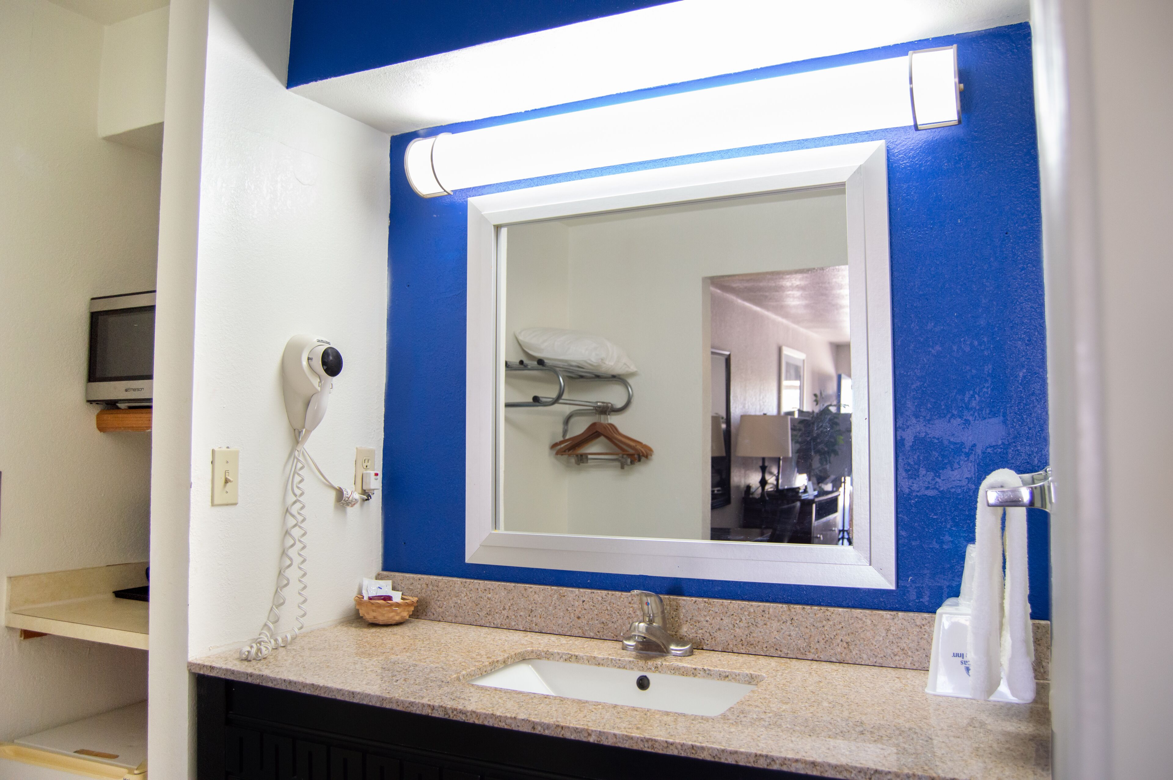 A bathroom with a sink, mirror, and towel dispenser.