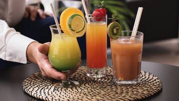Three drinks on a woven placemat with straws.