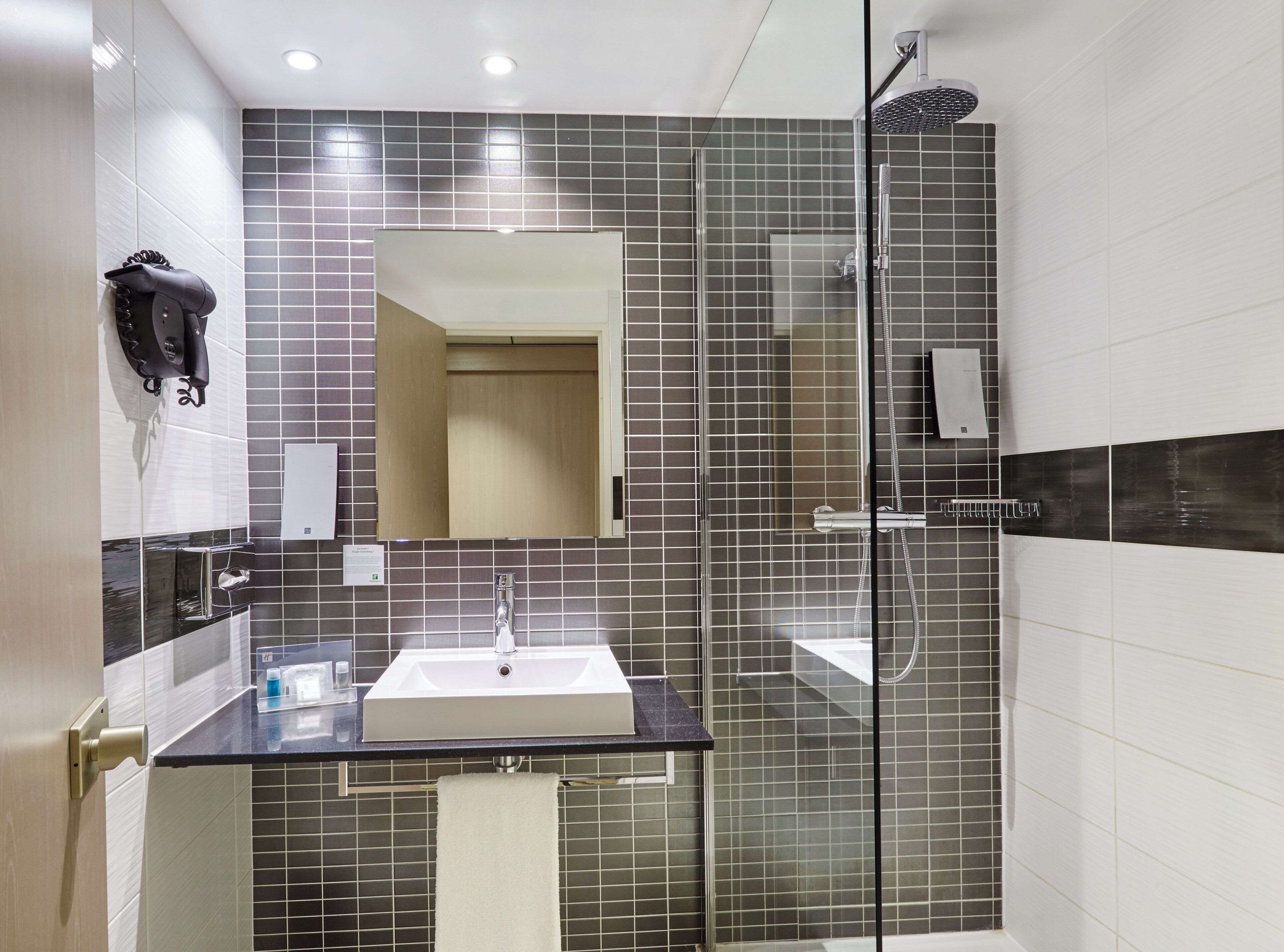 A modern bathroom with a glass-enclosed shower, a sink with a mirror above it, and a towel rack.
